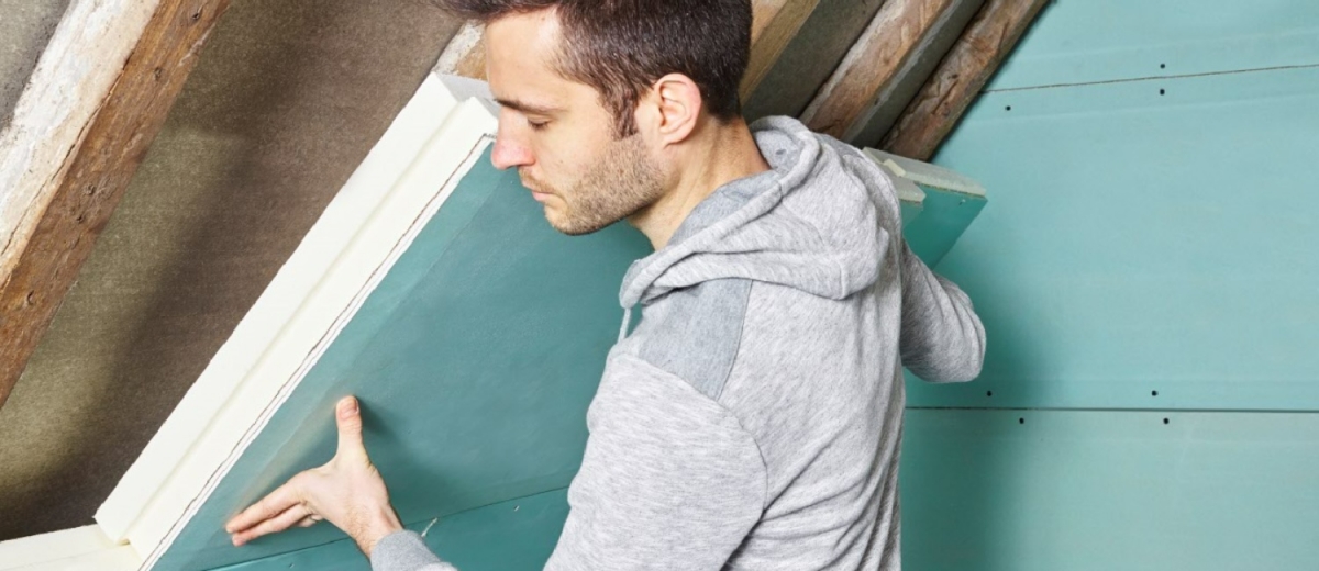 Installation d'un complexe isolant Unilin Une personne posant des complexes isolants Unilin afin de procéder à l'isolation par l'intérieur (ITI) de sa toiture.
